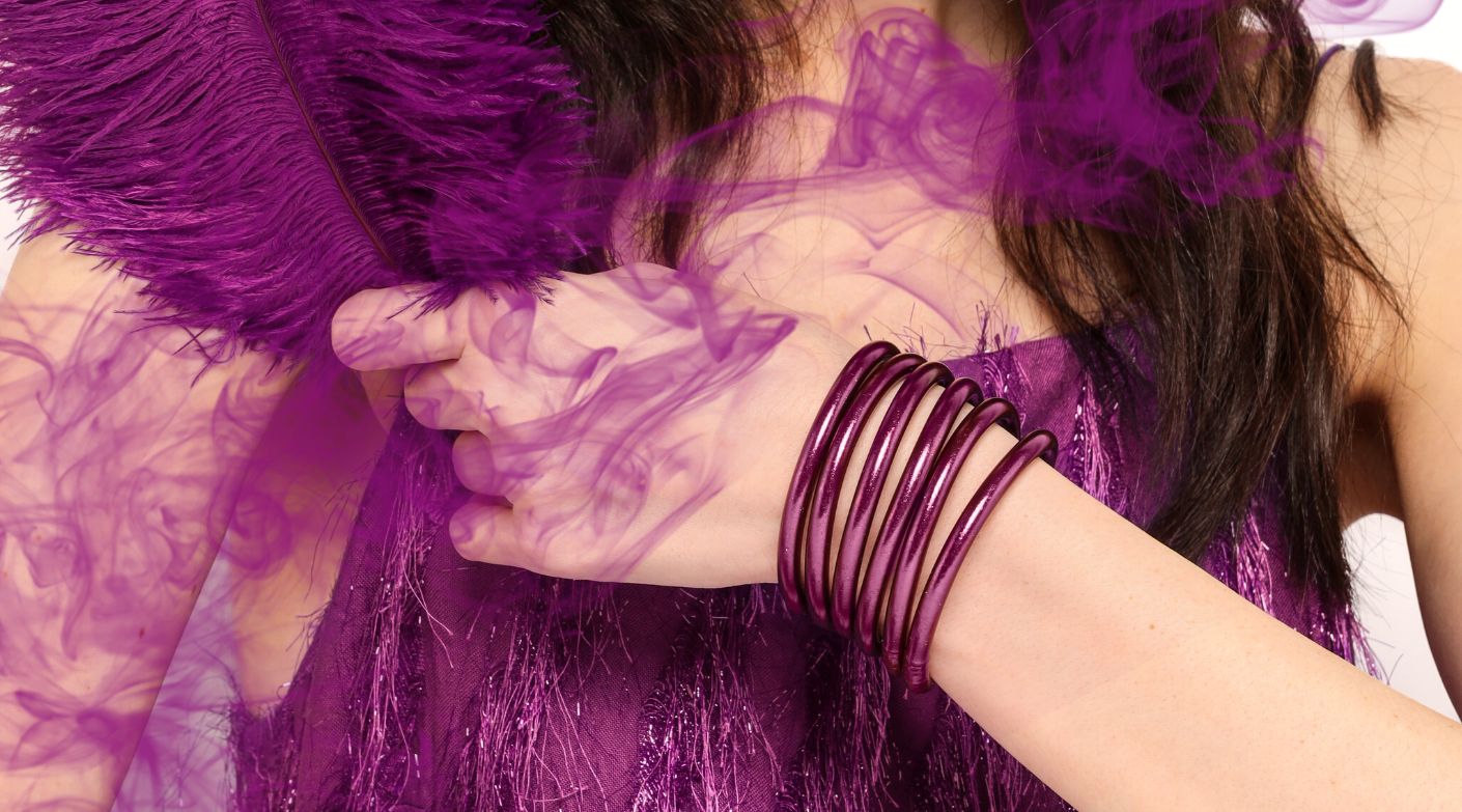 Woman in purple dress holding purple feather wearing BuDhaGirl Purple Amethyst All Weather Bangles | BuDhaBrief by BuDhaGirl