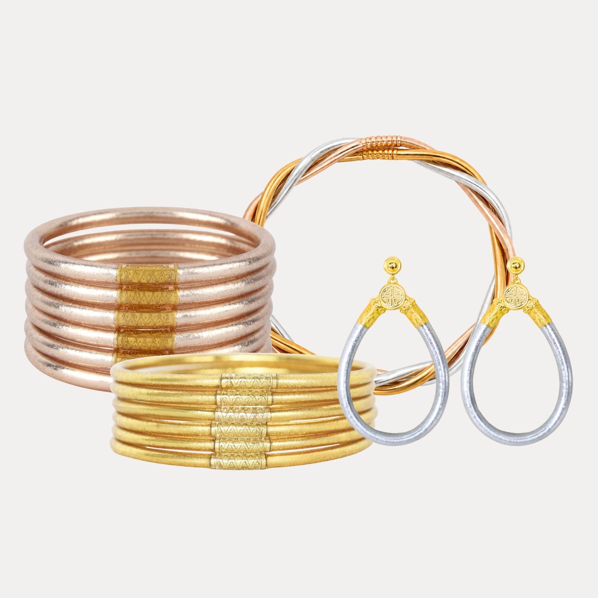 Set of gold and rose gold bangles and earrings on a light beige background
