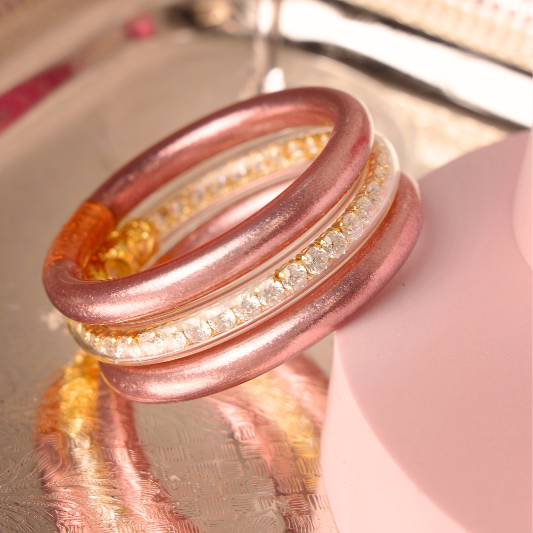 Stack of rose gold rings with gemstones on a reflective surface