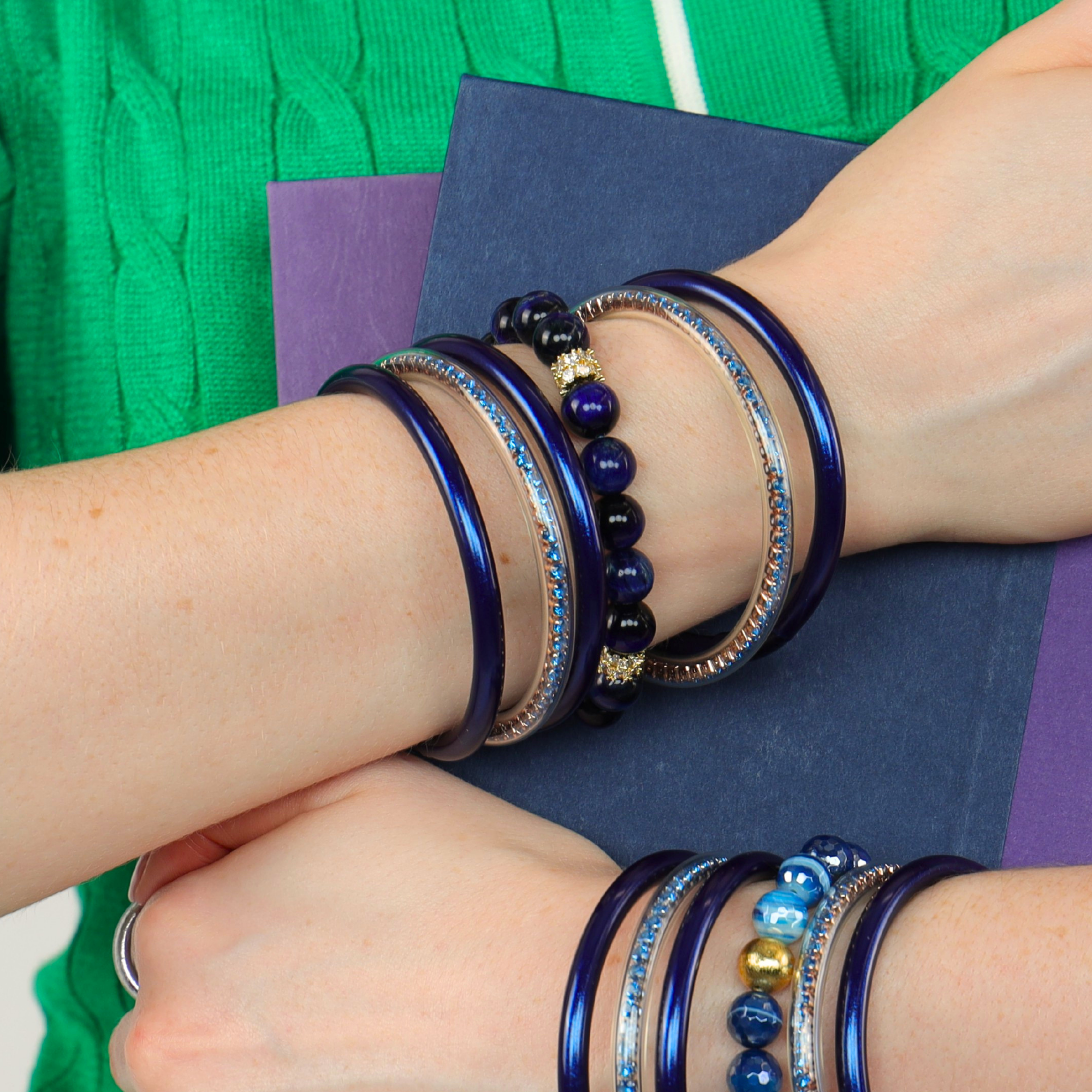 Handcrafted Cosmos Bracelet displayed with various bangle bracelets, showcasing rich midnight-blue tones and gold accents.