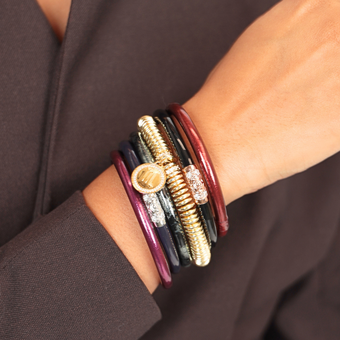 BuDhaGirl stack of six bangle bracelets for women in burgundy navy black and gold with decorative charms worn on a wrist