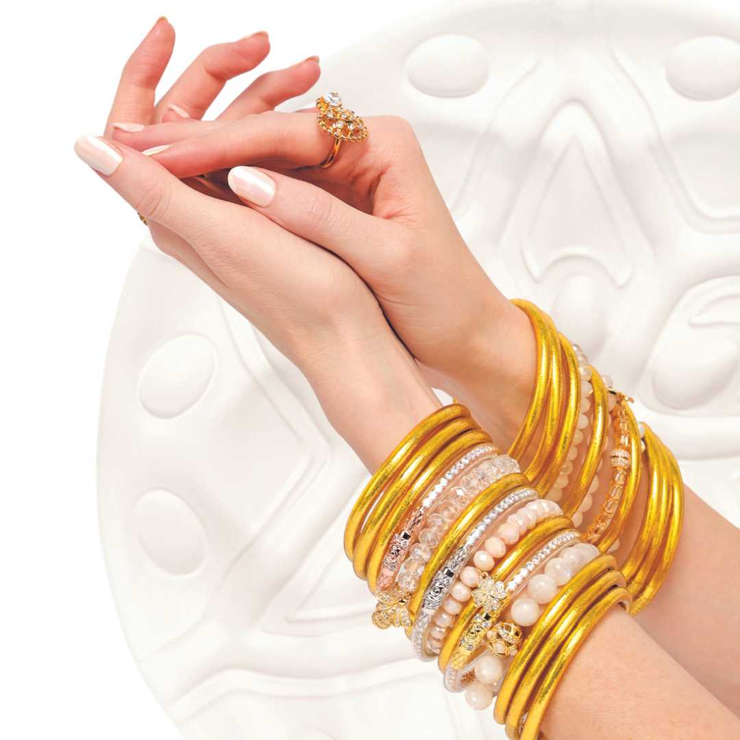 Gold Bangle Bracelet Stack on Hands in Front of White Circle Sculpture | BuDhaGirl