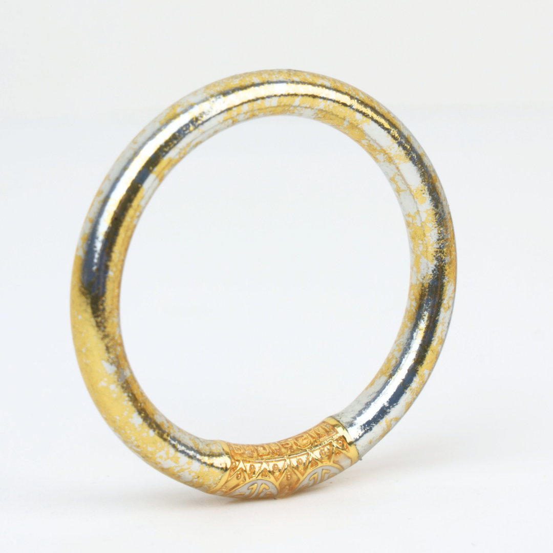 Gold and silver bangle bracelet with a marbled finish and ornate engraved center displayed against a white background