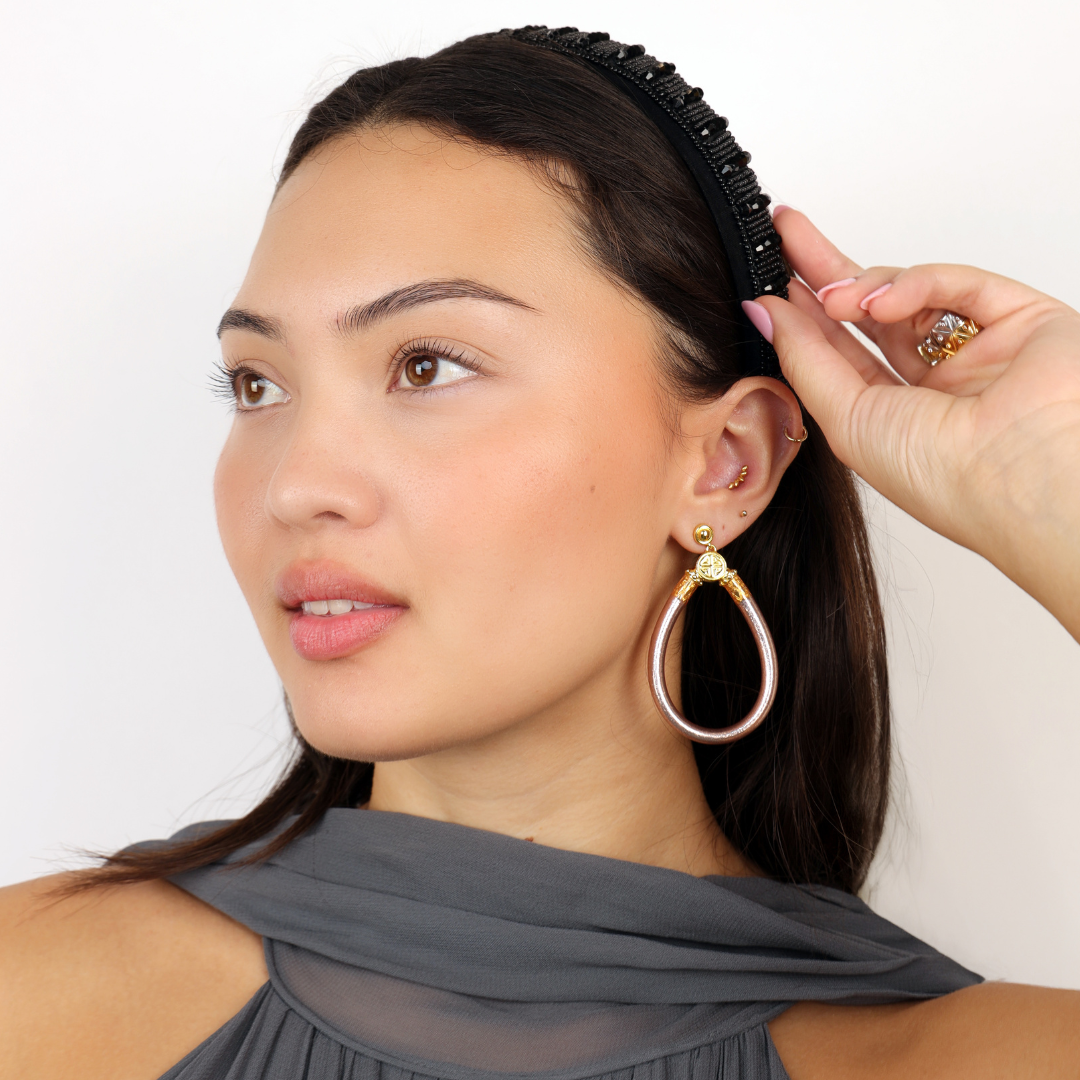 a woman with a black hair band and earrings