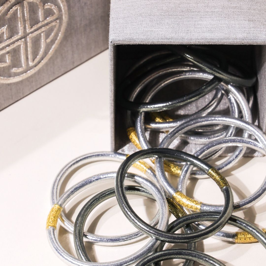 Black and grey bangles pictured next to a jewelry storage box called a coffret.