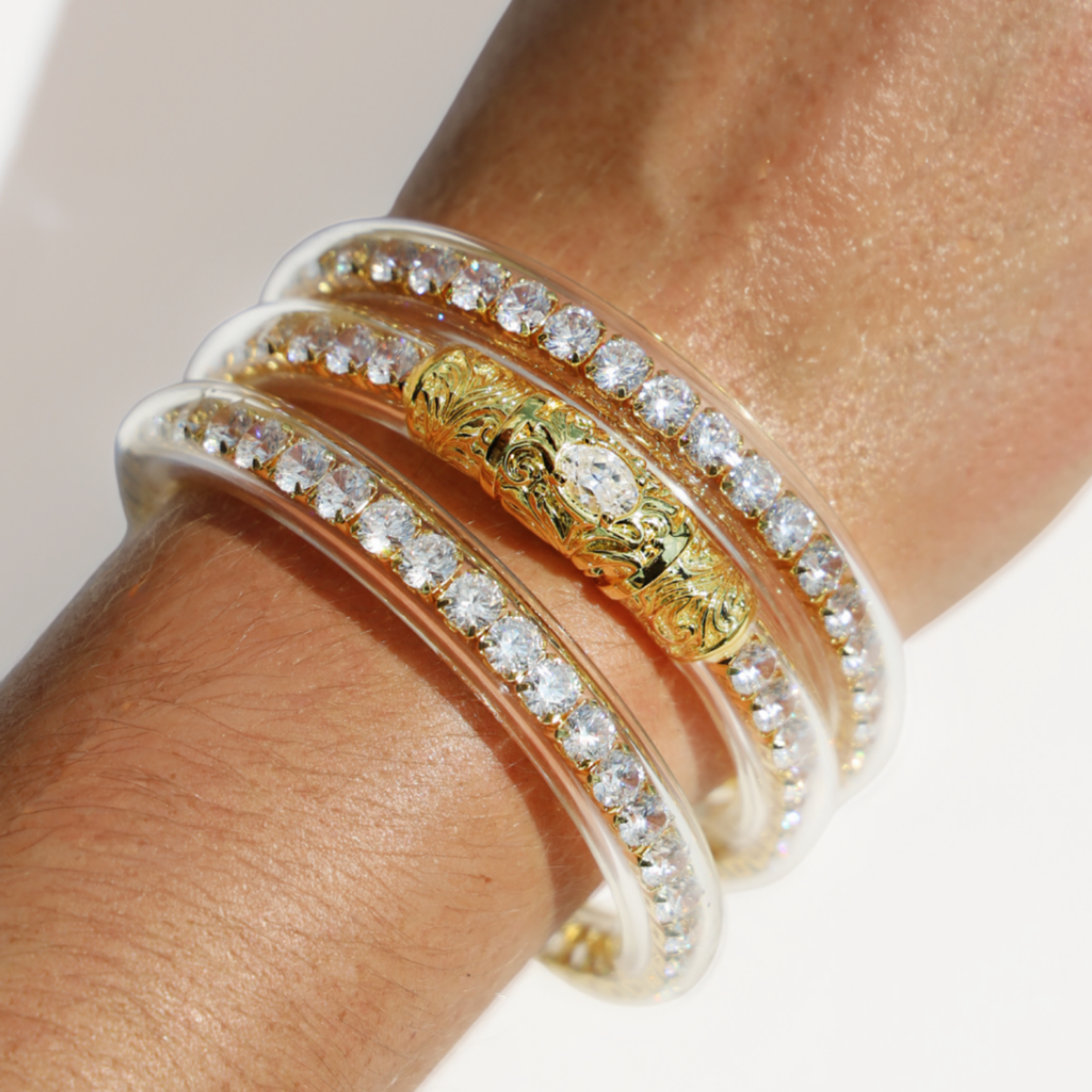 BuDhaGirl bangle bracelets for women stacked on a wrist with champagne toned bands crystal accents and an ornate gold engraved center piece