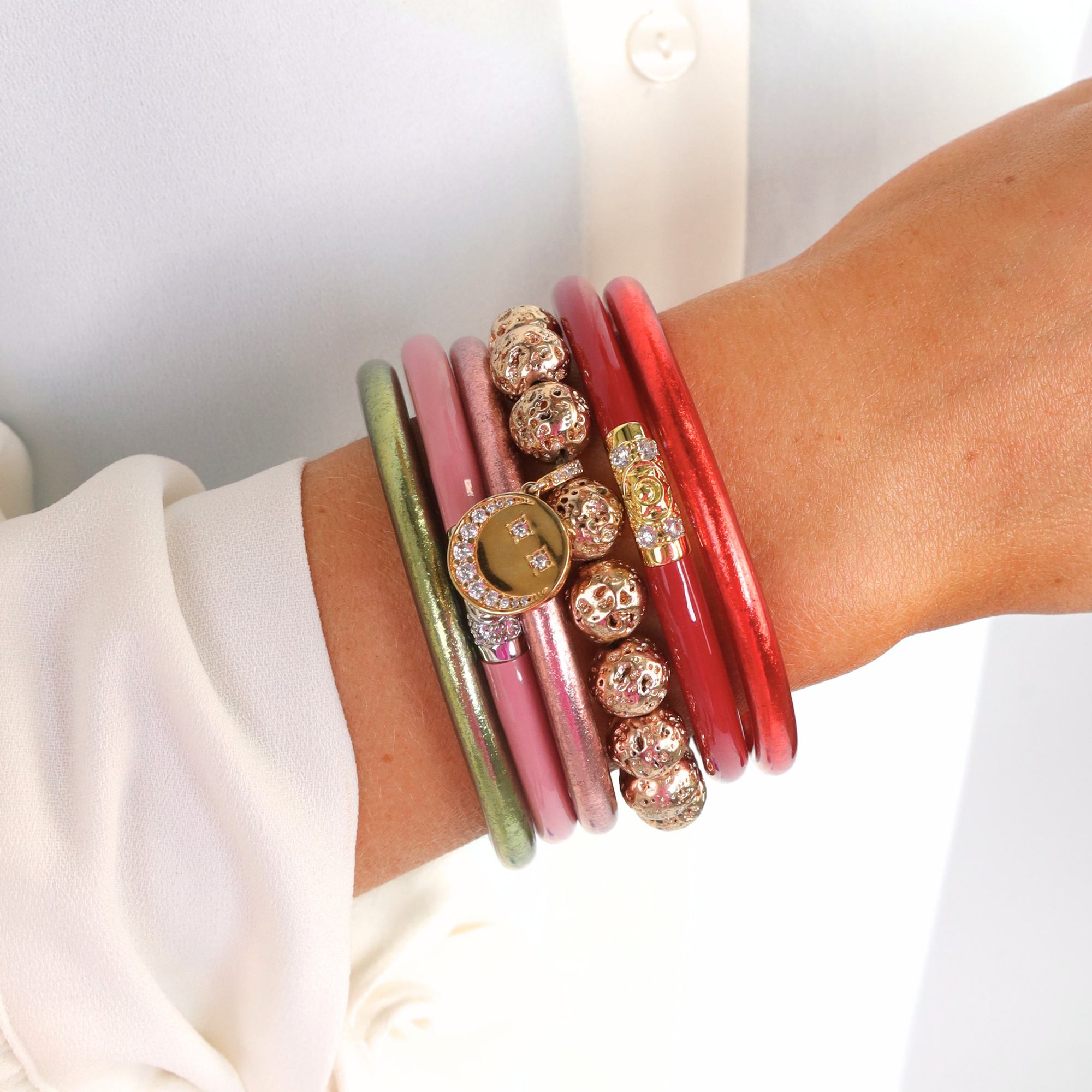 Close-up of a wrist wearing multiple colorful bracelets on a white background