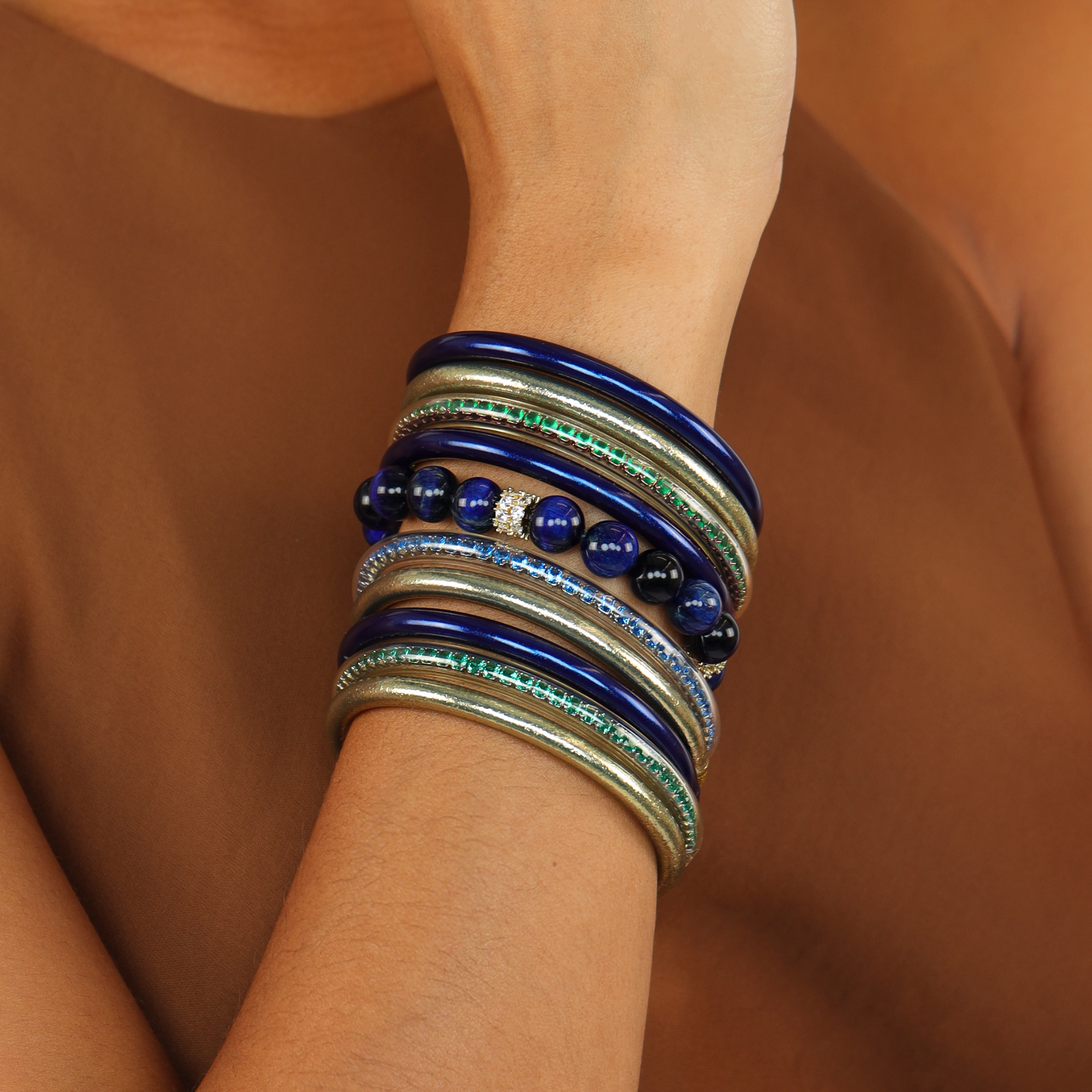 Cosmos Bracelet showcasing layered midnight-blue beaded stones and gold accents on a model's wrist.