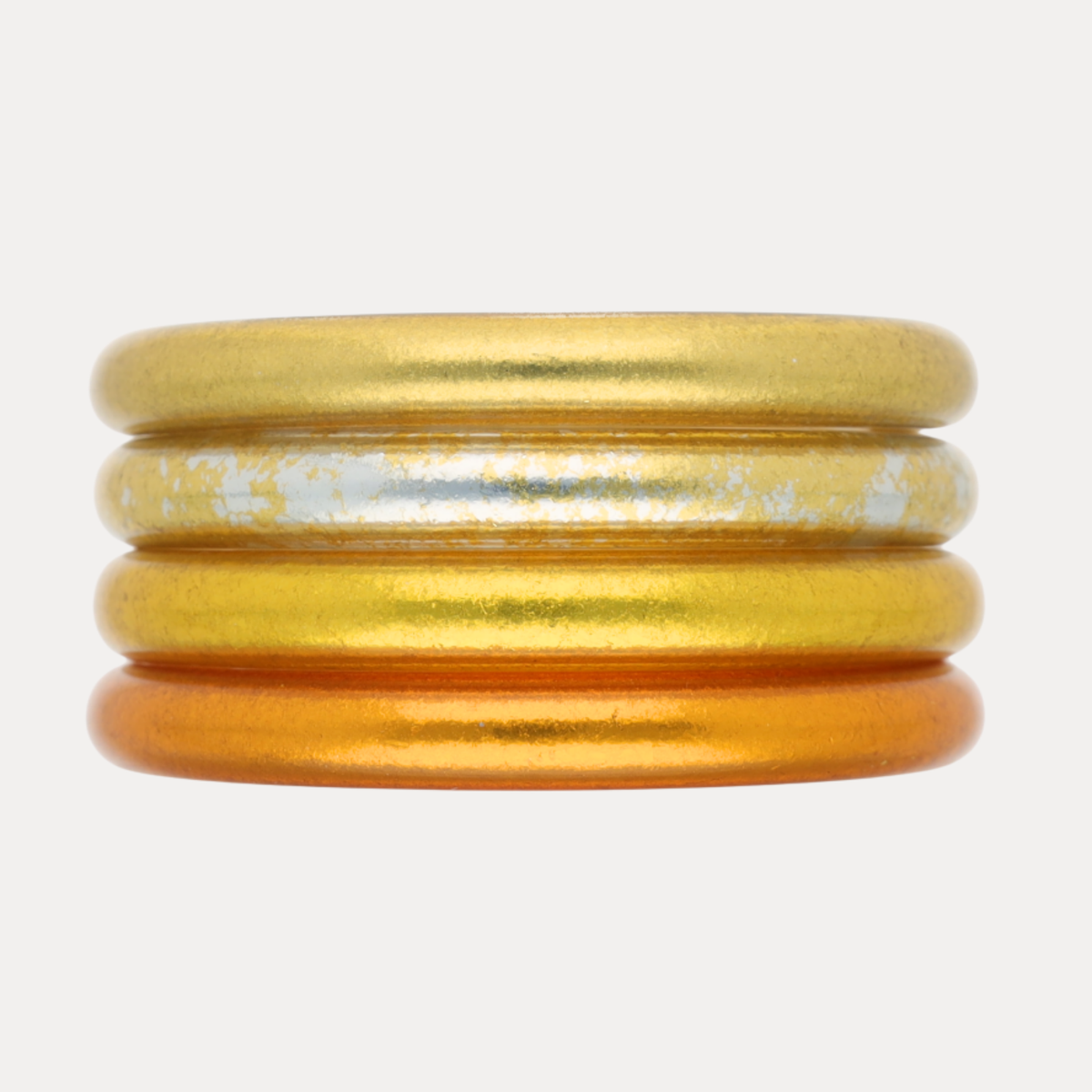 BuDhaGirl stack of four bangle bracelets for women in champagne gold shimmer and warm amber tones on a light background
