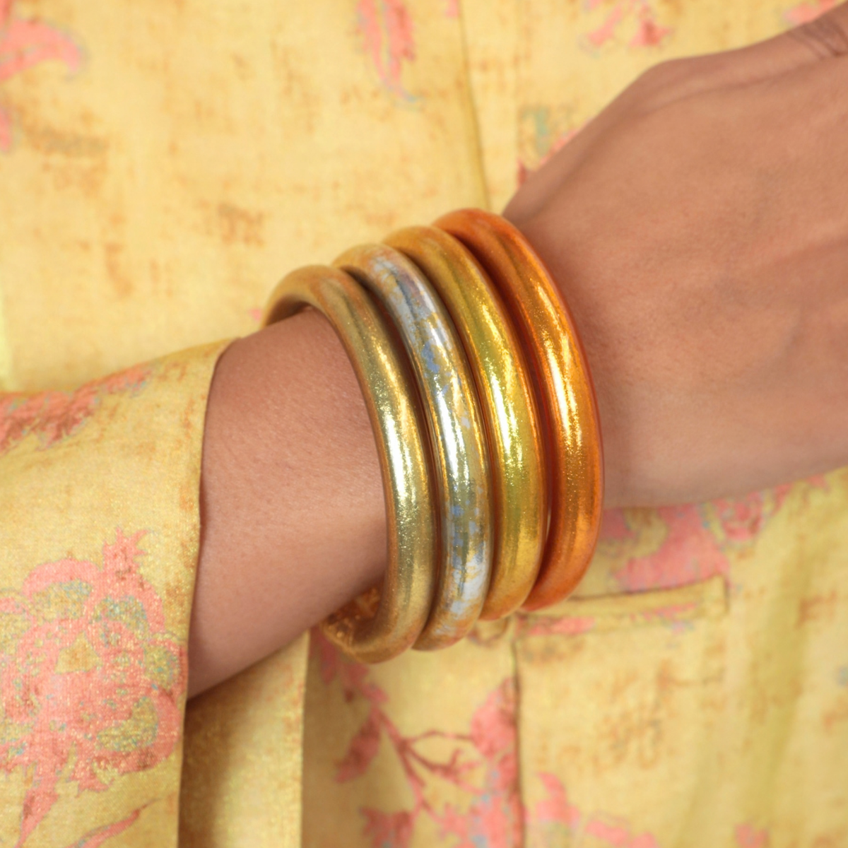 BuDhaGirl Bangle Bracelets For Women featuring four metallic bangles in gold silver bronze and warm amber tones worn on a wrist with a floral sleeve