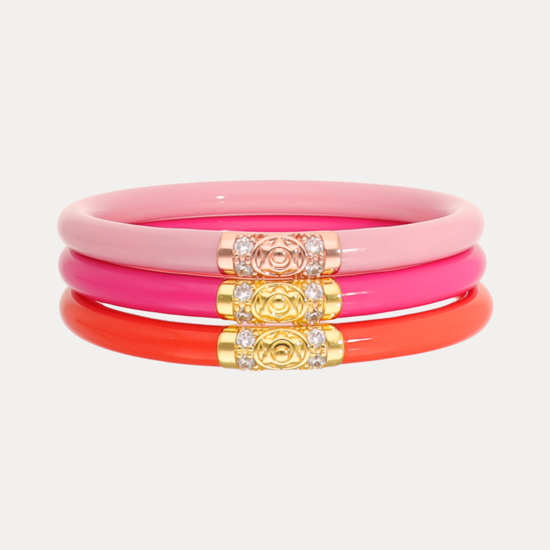 Set of pink and orange bangles with gold accents on a light gray background