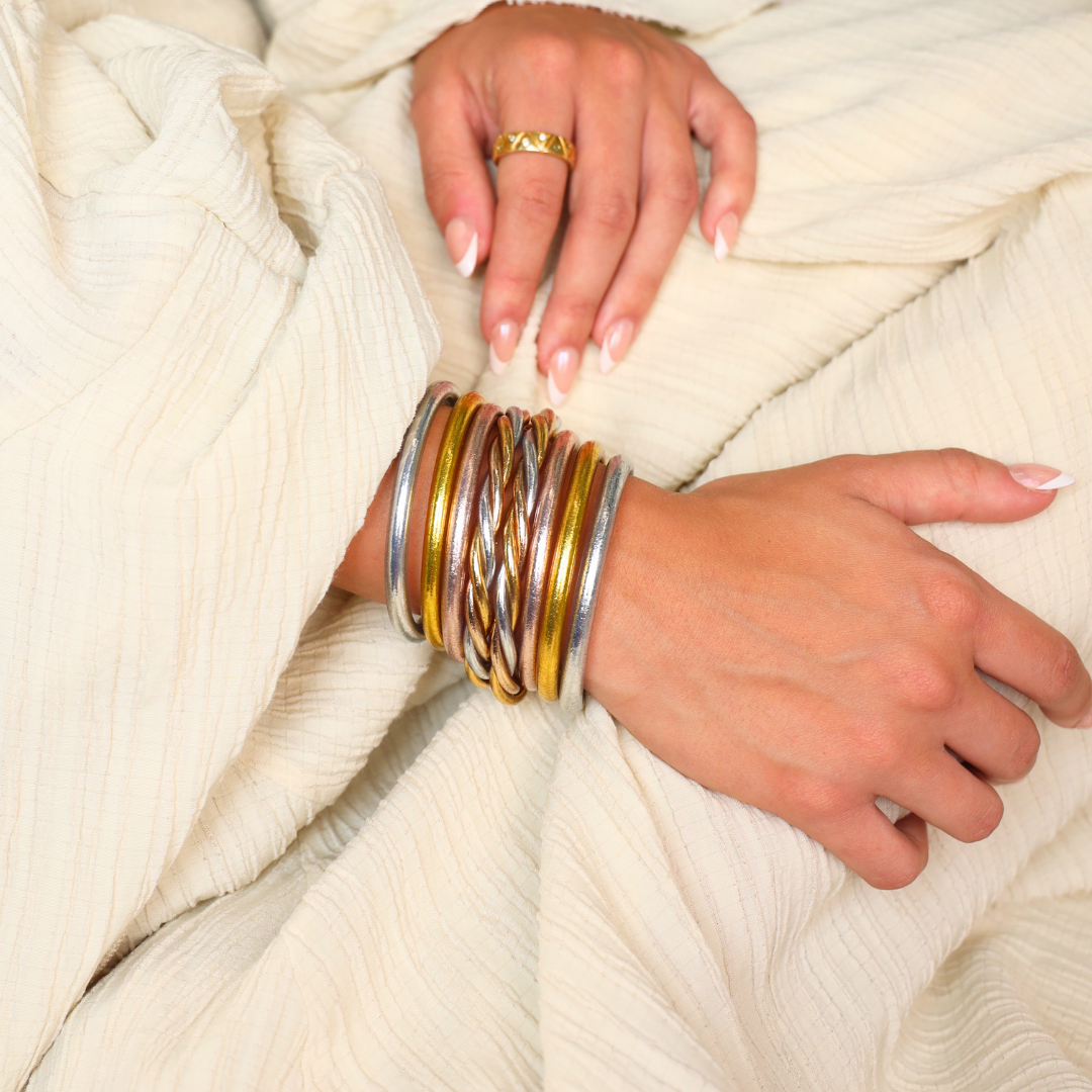 a hand with gold and silver bracelets